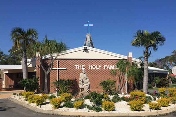 Exterior of Holy Family Catholic Parish church building with cross and statue, highlighting place of worship and connection to the local faith community