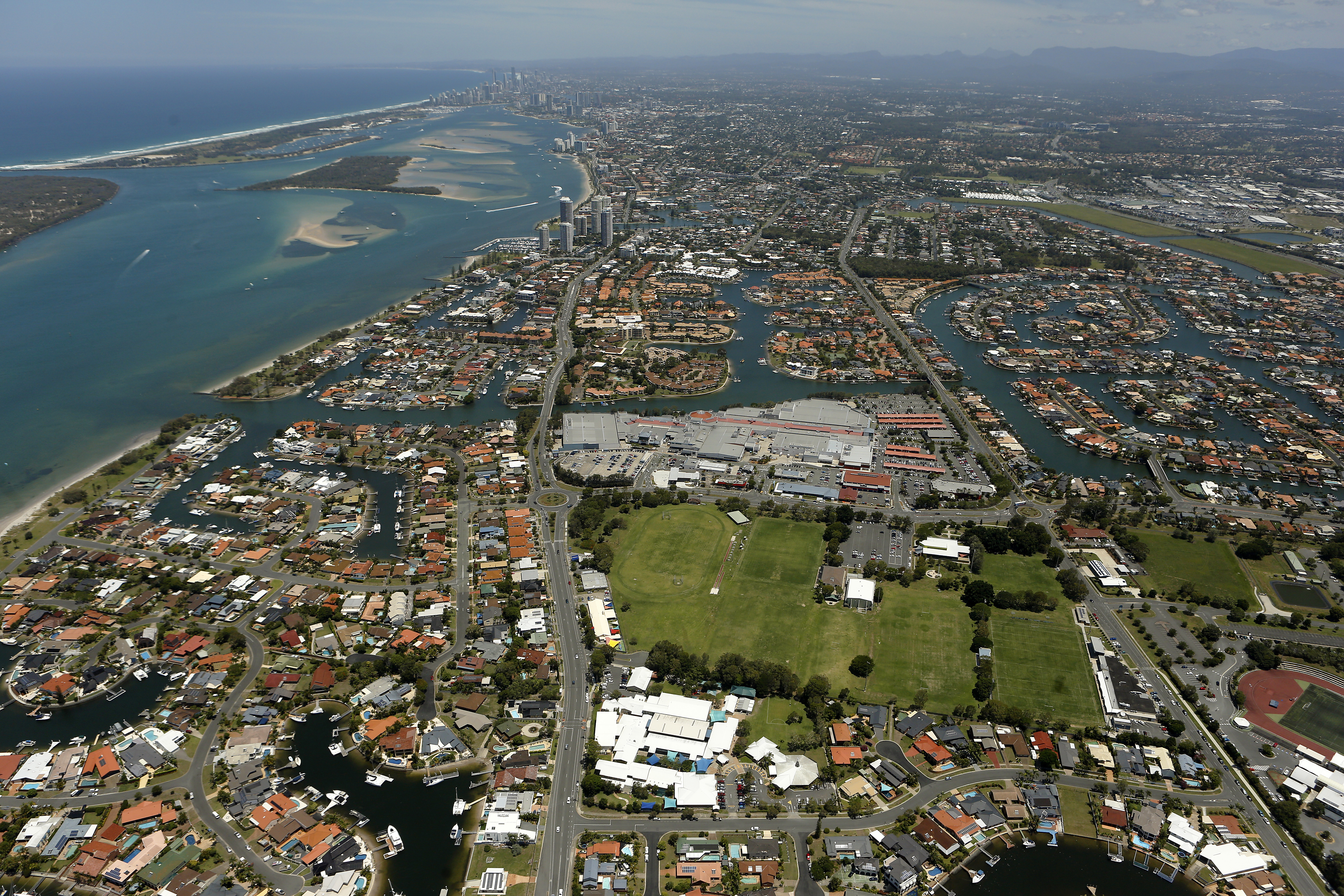 Aerial view of a coastal urban area showing waterways residential canal housing and nearby high rise skyline highlighting location context surrounding community and proximity to the coastline