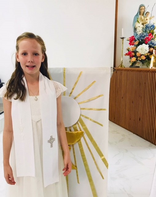 Student in formal attire standing in a church space during a sacramental celebration, highlighting faith formation and participation in Catholic traditions